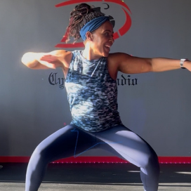 A woman practicing yoga at home with a laptop, focusing on fitness and mindfulness.